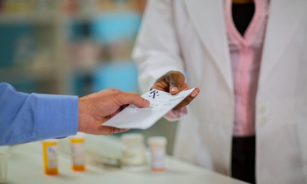 A doctor hands a prescription to a patient.